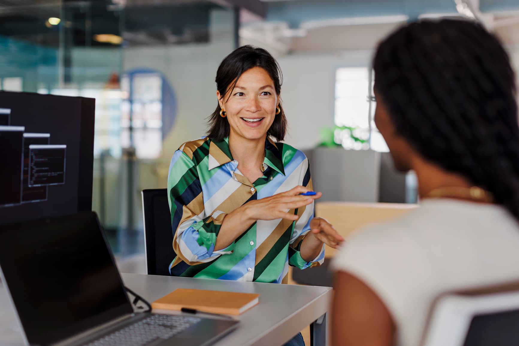 Two colleagues in conversation at a workstation